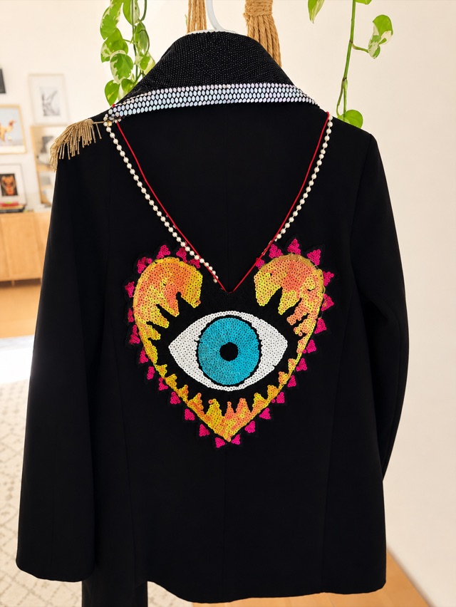 Glow in the Dark, a long black coat with a beaded eye and heart across the back